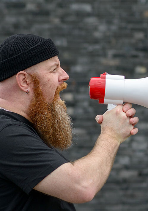 Man with a grievance yelling into a megaphone pointed to copy space at a rally, strike or demonstration in panorama banner format